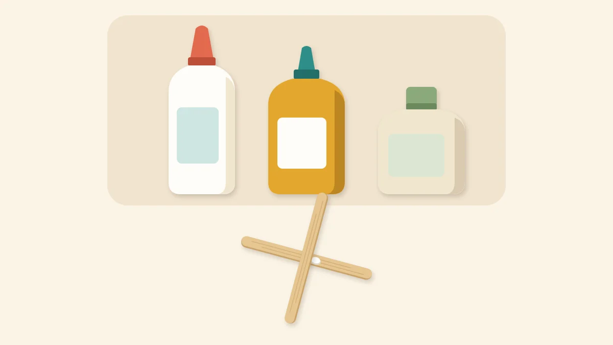 Three unlabeled glue bottles behind two craft sticks glued in a cross