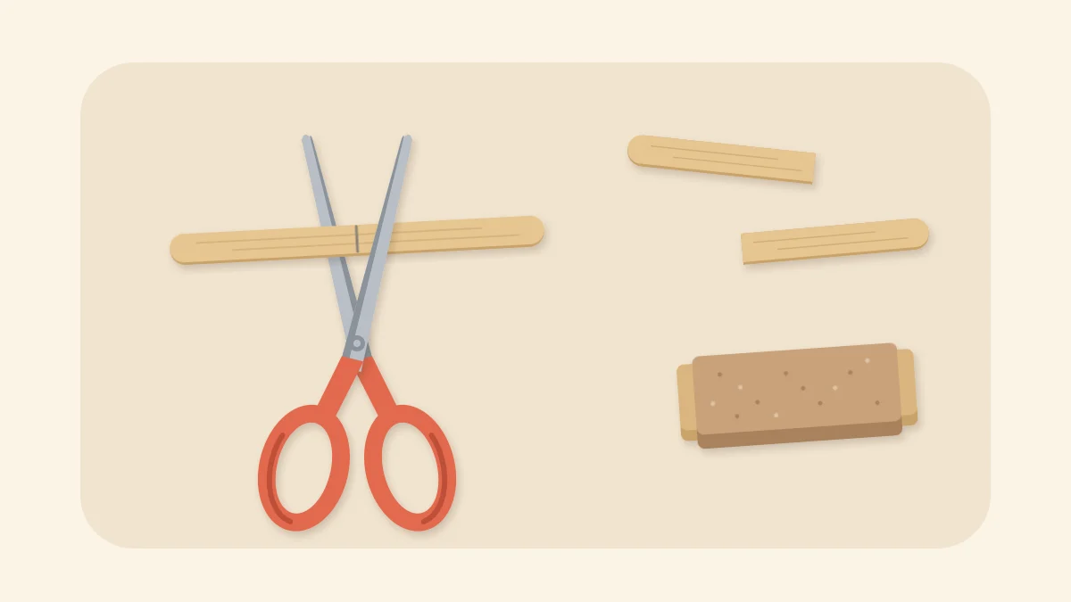 Scissors cutting a craft stick at a pencil mark, with two cut halves and a sanding block