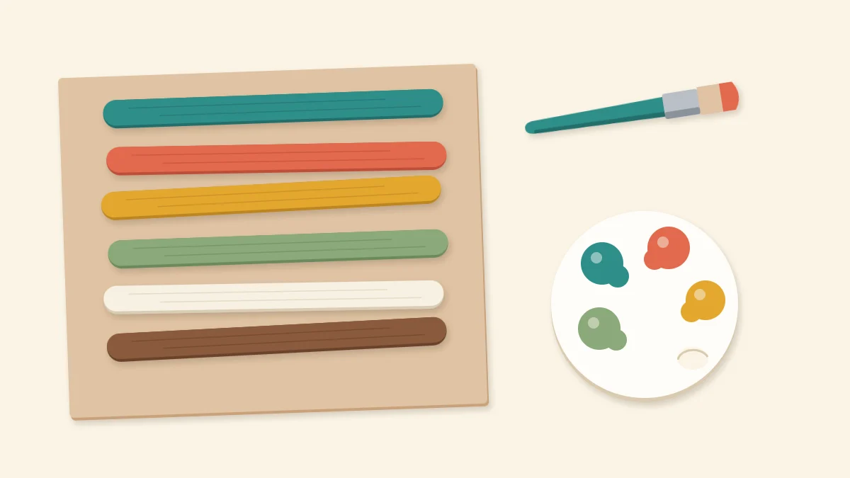 Six craft sticks painted in different colors on scrap paper beside a brush and palette