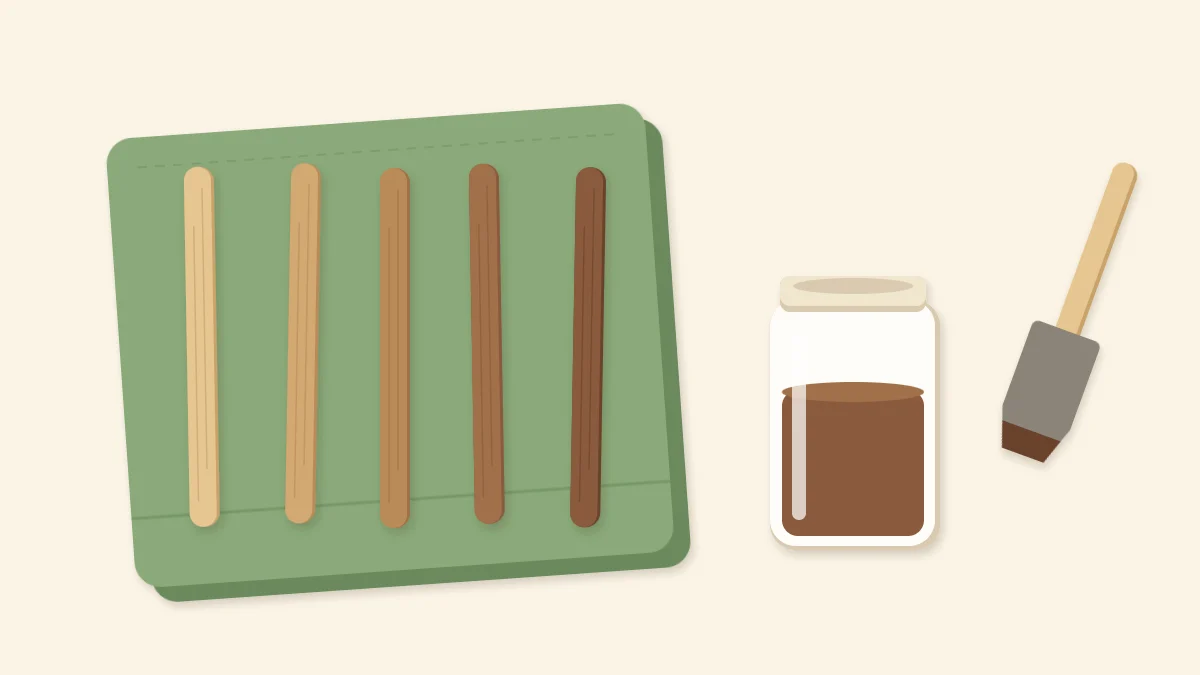 Five craft sticks stained from pale to dark walnut on a rag beside a jar of stain and a foam brush
