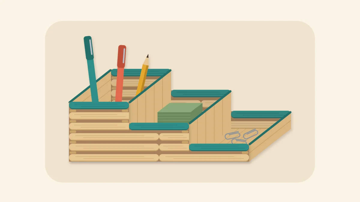 Three-compartment popsicle stick desk organizer holding pens, a note block and paper clips